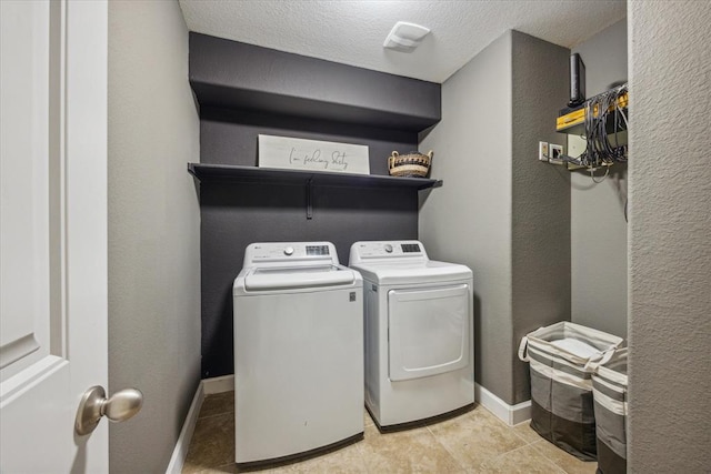washroom with a textured ceiling, light tile patterned floors, baseboards, laundry area, and independent washer and dryer