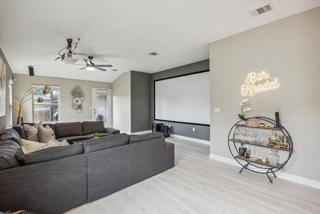 home theater with baseboards, visible vents, and light wood-style floors