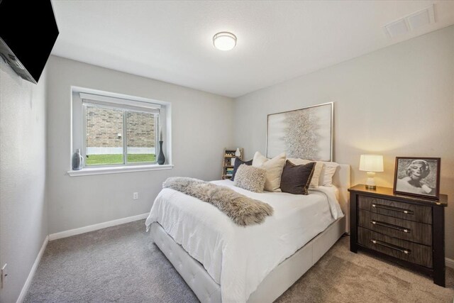 bedroom with baseboards, visible vents, and light colored carpet