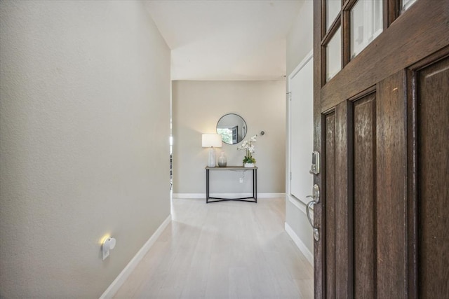 corridor featuring light wood-style flooring and baseboards