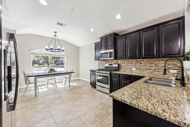 kitchen featuring visible vents, appliances with stainless steel finishes, light stone countertops, vaulted ceiling, and a sink