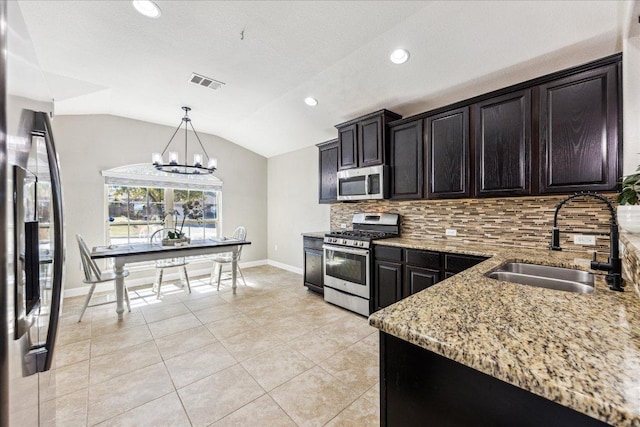 kitchen with light stone counters, stainless steel appliances, visible vents, a sink, and decorative backsplash