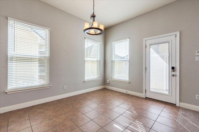 unfurnished room with tile patterned flooring, baseboards, and an inviting chandelier