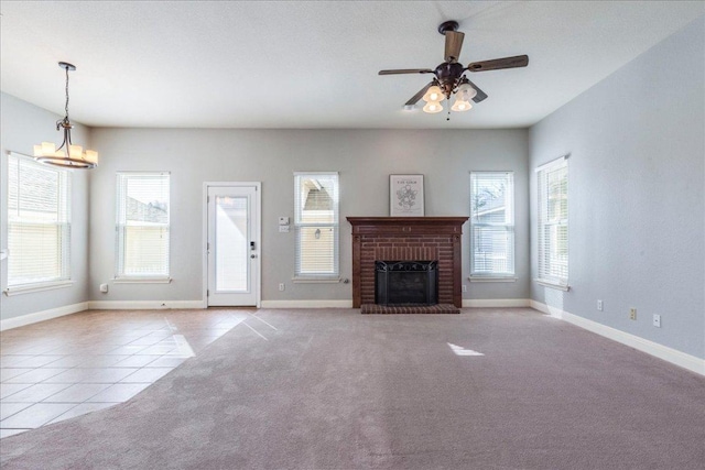 unfurnished living room with carpet floors, a ceiling fan, baseboards, a brick fireplace, and tile patterned floors