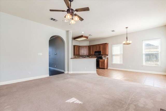 unfurnished living room featuring arched walkways, light tile patterned floors, visible vents, light carpet, and ceiling fan