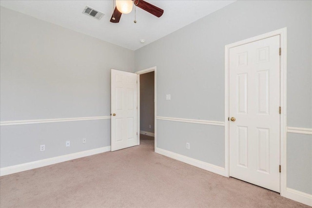 carpeted spare room featuring baseboards, visible vents, and ceiling fan