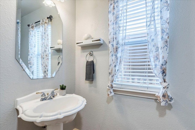 bathroom with a sink, a wealth of natural light, and a textured wall