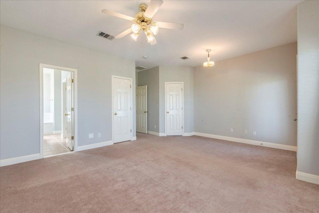 unfurnished bedroom with ceiling fan, ensuite bathroom, light carpet, visible vents, and baseboards