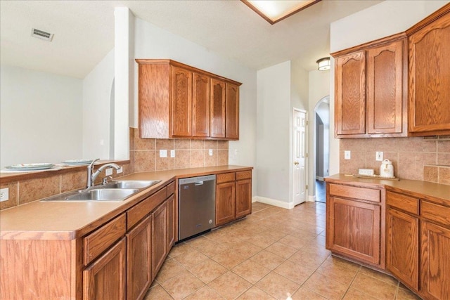 kitchen featuring stainless steel dishwasher, brown cabinetry, a sink, and visible vents