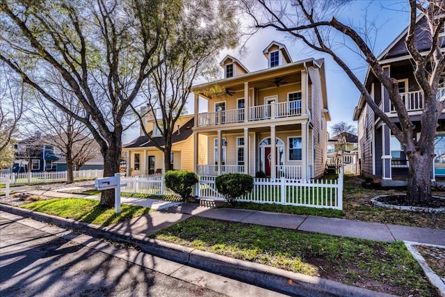 view of front of property featuring a balcony, a fenced front yard, a porch, and a ceiling fan