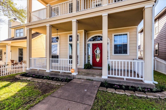 view of exterior entry featuring a chimney, fence, and a porch