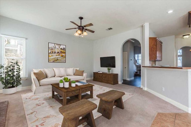 living area featuring visible vents, arched walkways, baseboards, and light colored carpet