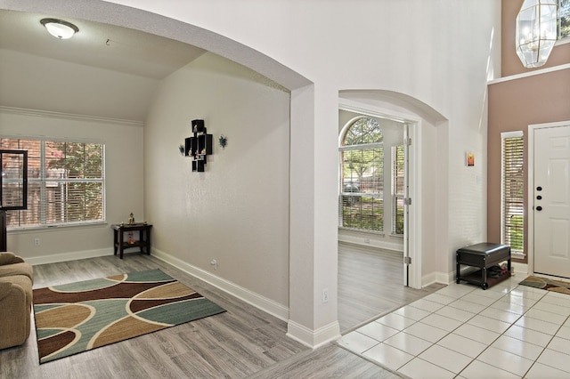 entrance foyer featuring baseboards, arched walkways, and wood finished floors