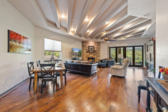 dining room with beam ceiling, a fireplace, hardwood / wood-style floors, a ceiling fan, and baseboards