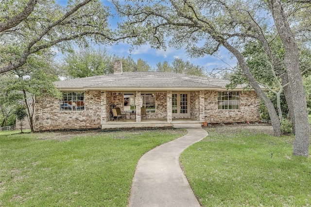 ranch-style house with a patio, a chimney, french doors, a front yard, and brick siding