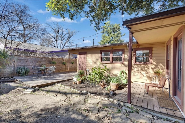 back of property with a patio area, outdoor dining space, fence, and a wooden deck