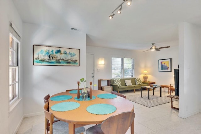 dining space featuring a ceiling fan, rail lighting, visible vents, and baseboards