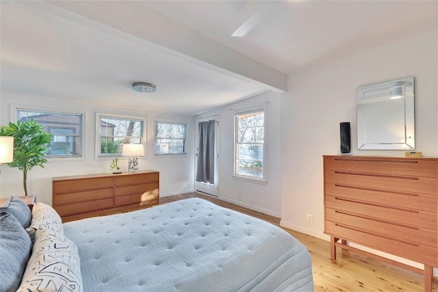 bedroom featuring access to exterior, beamed ceiling, baseboards, and wood finished floors