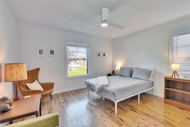 bedroom with ceiling fan, light wood finished floors, and baseboards