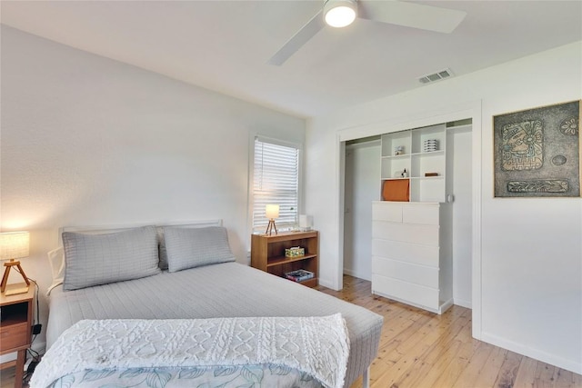 bedroom featuring baseboards, visible vents, a ceiling fan, wood finished floors, and a closet