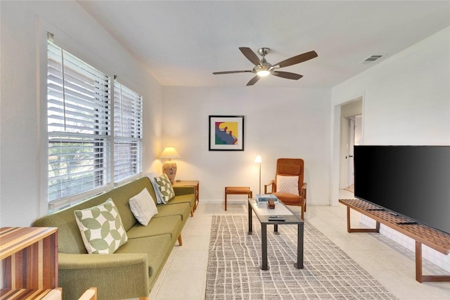 living room with light tile patterned floors, visible vents, and a ceiling fan