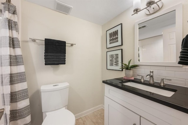 bathroom featuring toilet, vanity, baseboards, visible vents, and decorative backsplash