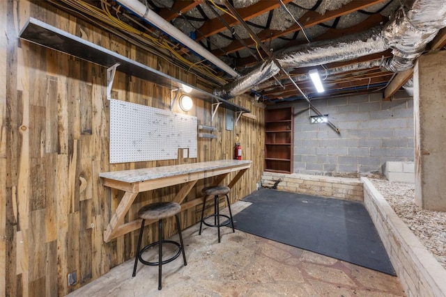 unfinished basement with concrete block wall and a workshop area