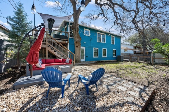 back of house featuring a deck, a fenced backyard, an outdoor hangout area, central AC, and stairs