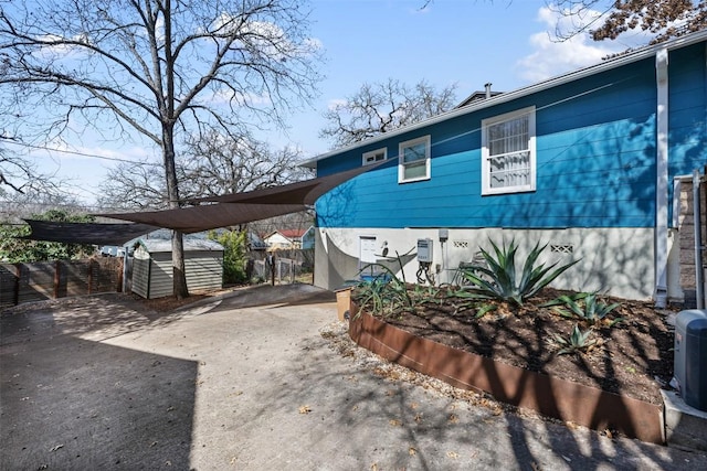 exterior space with driveway, a carport, and fence