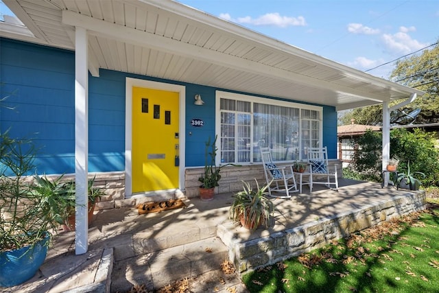 doorway to property with a porch and stone siding