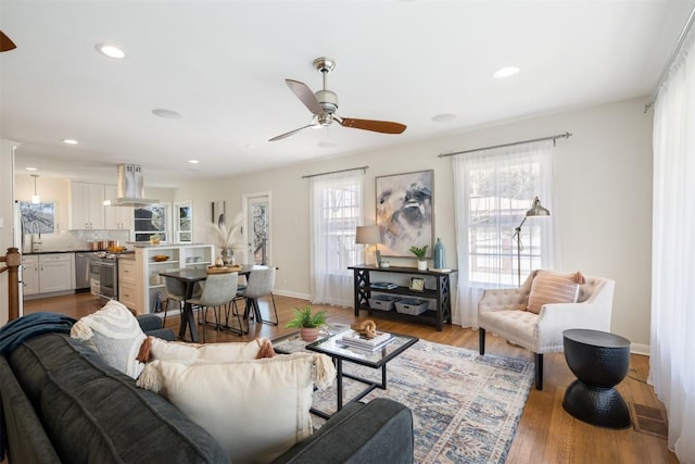 living room with ceiling fan, light wood-style flooring, recessed lighting, visible vents, and baseboards