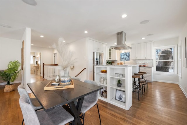 dining room featuring baseboards, wood finished floors, and recessed lighting