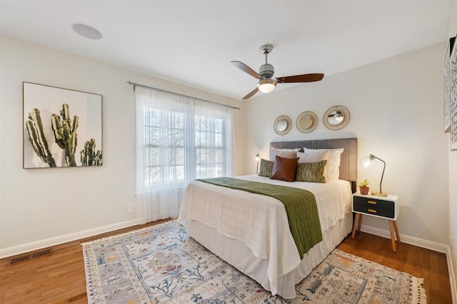 bedroom featuring visible vents, ceiling fan, baseboards, and wood finished floors