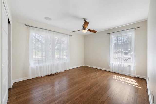 unfurnished room with wood finished floors, a ceiling fan, and baseboards