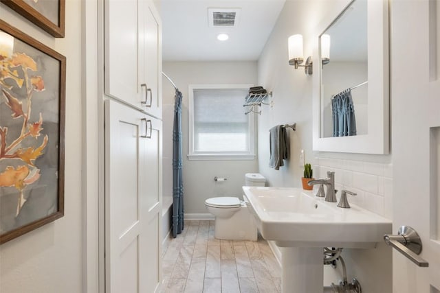 full bath with toilet, shower / bathtub combination with curtain, visible vents, and tasteful backsplash