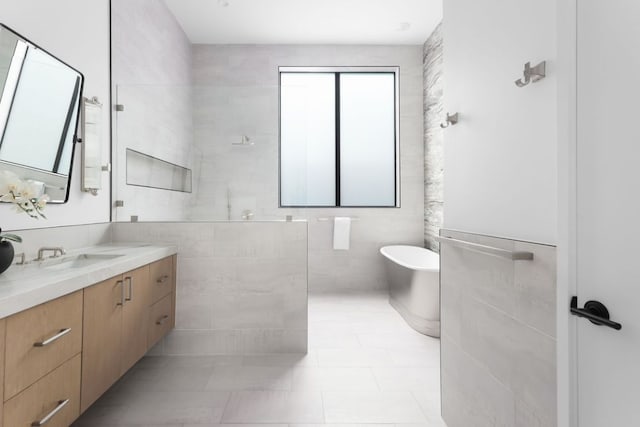 bathroom featuring tile walls, tile patterned floors, a freestanding bath, vanity, and walk in shower