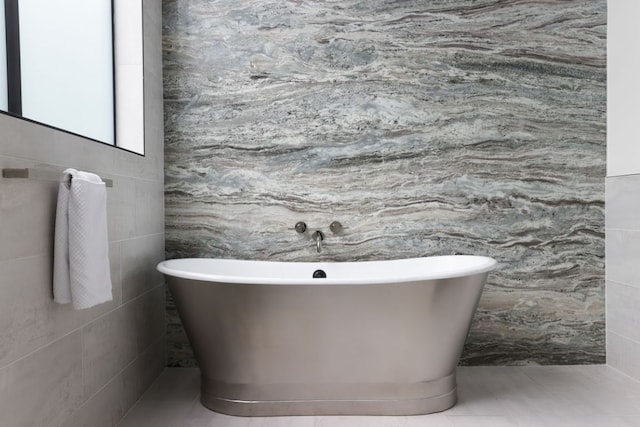 bathroom featuring a freestanding bath, tile walls, and tile patterned floors