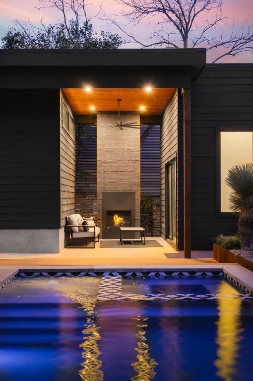 1704 Newton St, Austin, TX 78704 - pool at dusk with a fireplace, an outdoor pool, and a patio area