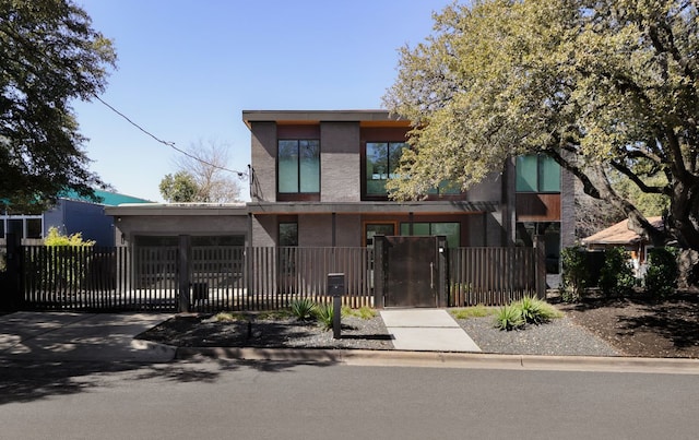 view of front of property with driveway, a fenced front yard, a garage, and a gate