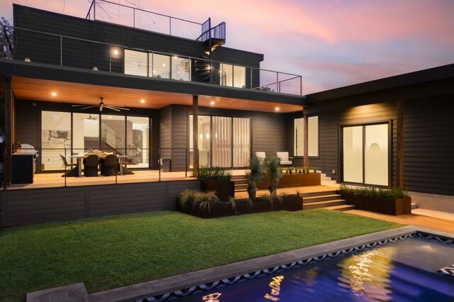 1704 Newton St, Austin, TX 78704 - back of property at dusk with a balcony, a yard, and ceiling fan