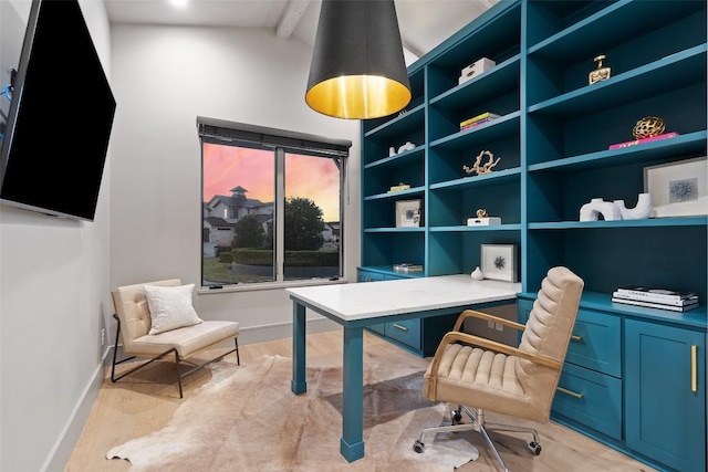 office area featuring vaulted ceiling with beams, light wood-style flooring, built in study area, and baseboards