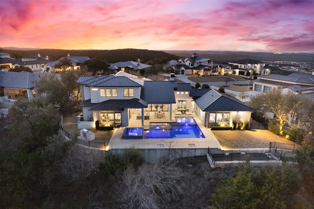 back of house featuring a standing seam roof, a fenced backyard, a patio area, a residential view, and metal roof