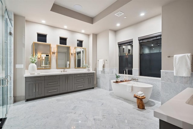 full bath featuring visible vents, tile walls, a stall shower, a freestanding tub, and vanity