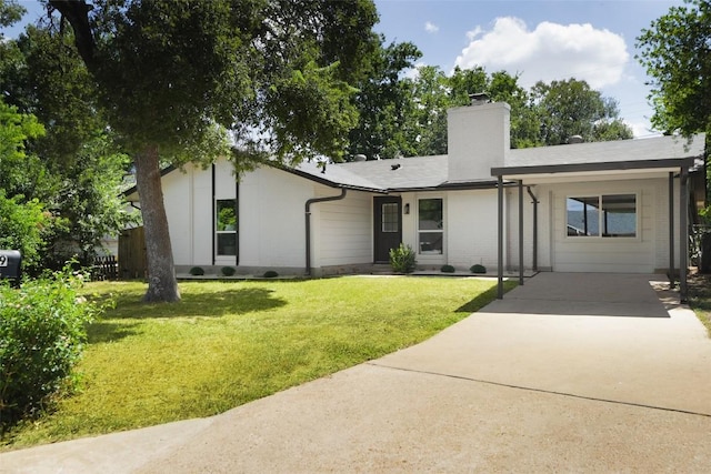 view of front of home featuring driveway, a chimney, and a front lawn