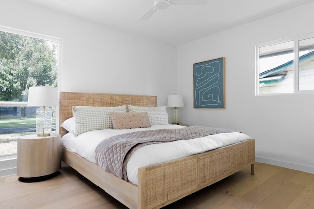 bedroom with multiple windows, ceiling fan, baseboards, and wood finished floors