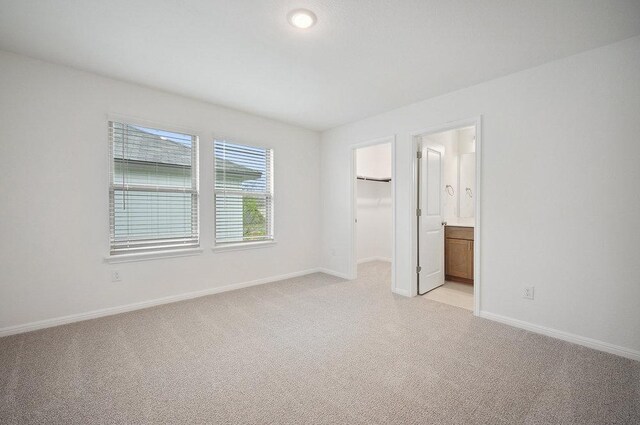 13224 Ditka Dr, Austin, TX 78652 - unfurnished bedroom with light colored carpet, baseboards, a spacious closet, ensuite bath, and a closet