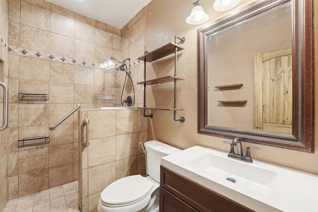 bathroom with a textured wall, a stall shower, vanity, and toilet