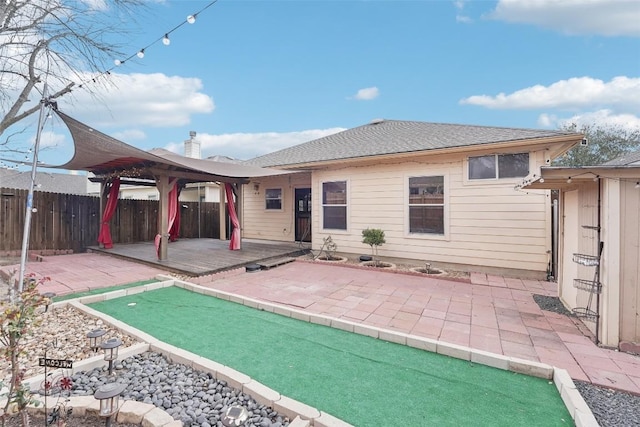 back of house with a shingled roof, a patio, and fence