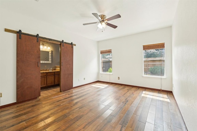 9316 Brents Elm Dr, Austin, TX 78744 - spare room with a barn door, plenty of natural light, ceiling fan, and wood finished floors