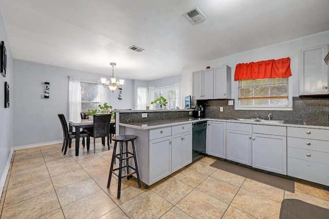 kitchen featuring a peninsula, black dishwasher, visible vents, and a sink